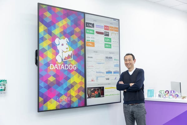 Datadogのエントランスにある大きなモニターの前で